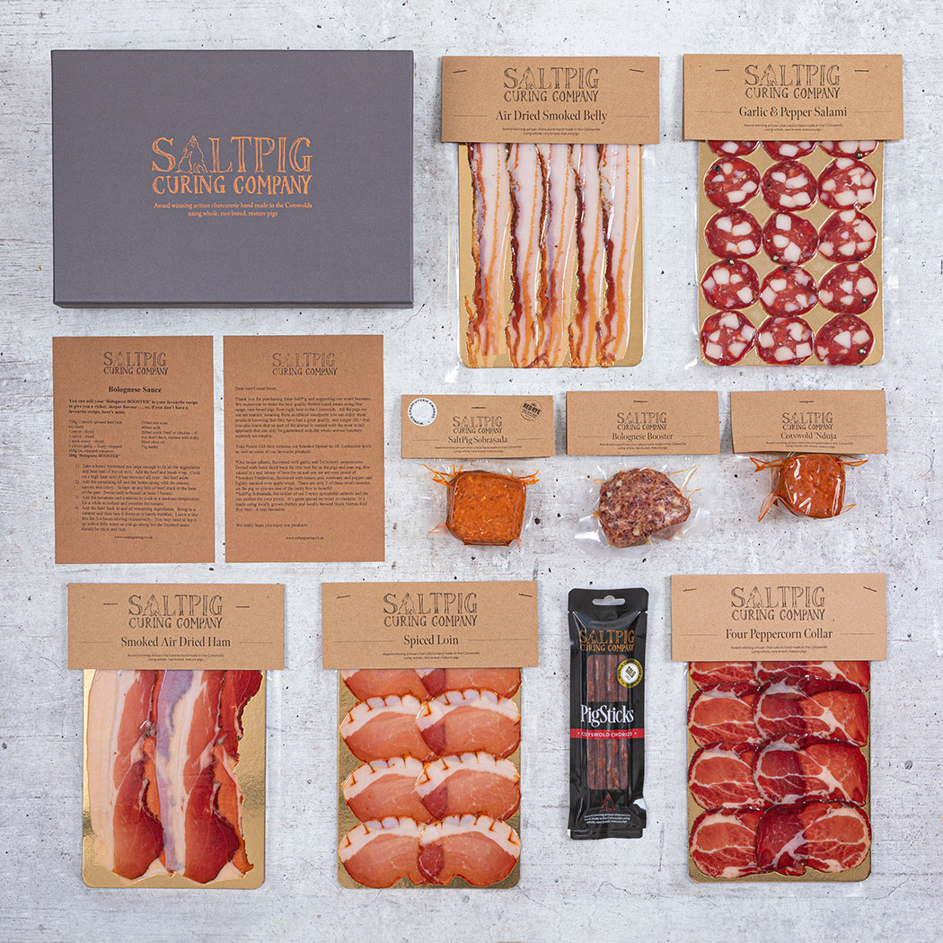 Saltpig cured meat box showing a selection of cured meats including salami and prosciutto displayed on a grey backdrop.