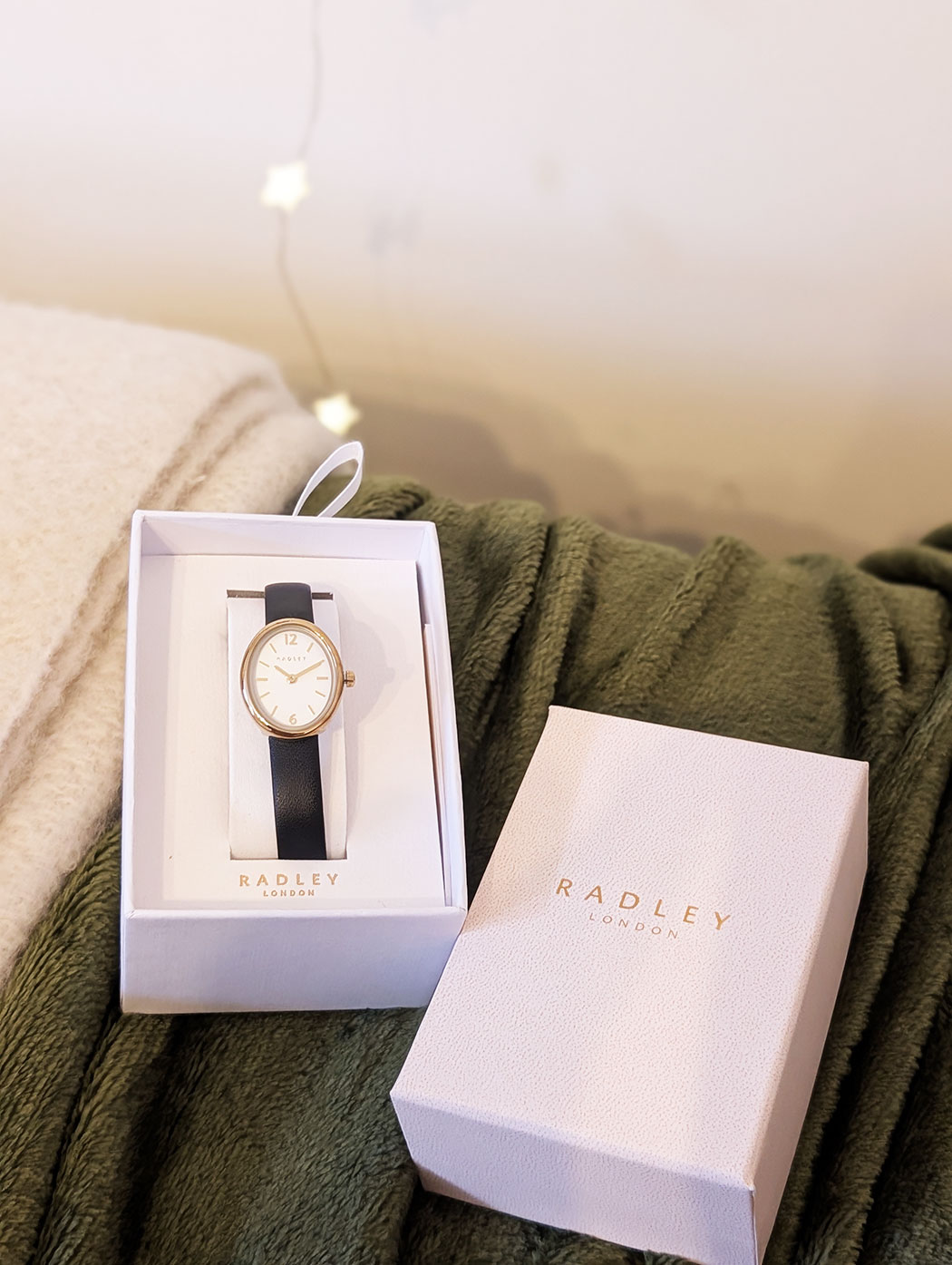 Radley watch with black strap and gold dial on soft green blanket