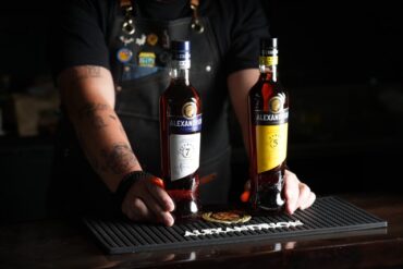 Image of a bartender holding two different bottles of brandy.