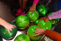 green bowling balls with women's hands holding on to them.
