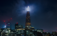 The Shard lit up at night against a city backdrop.