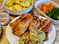 roast dinner with roast chicken and sausages on a white plate