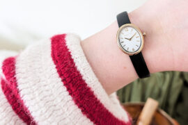 womens watch on ladies wrist wearing red and white striped cardigan