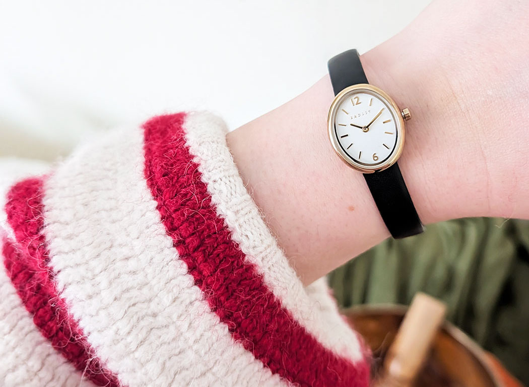 womens watch on ladies wrist wearing red and white striped cardigan